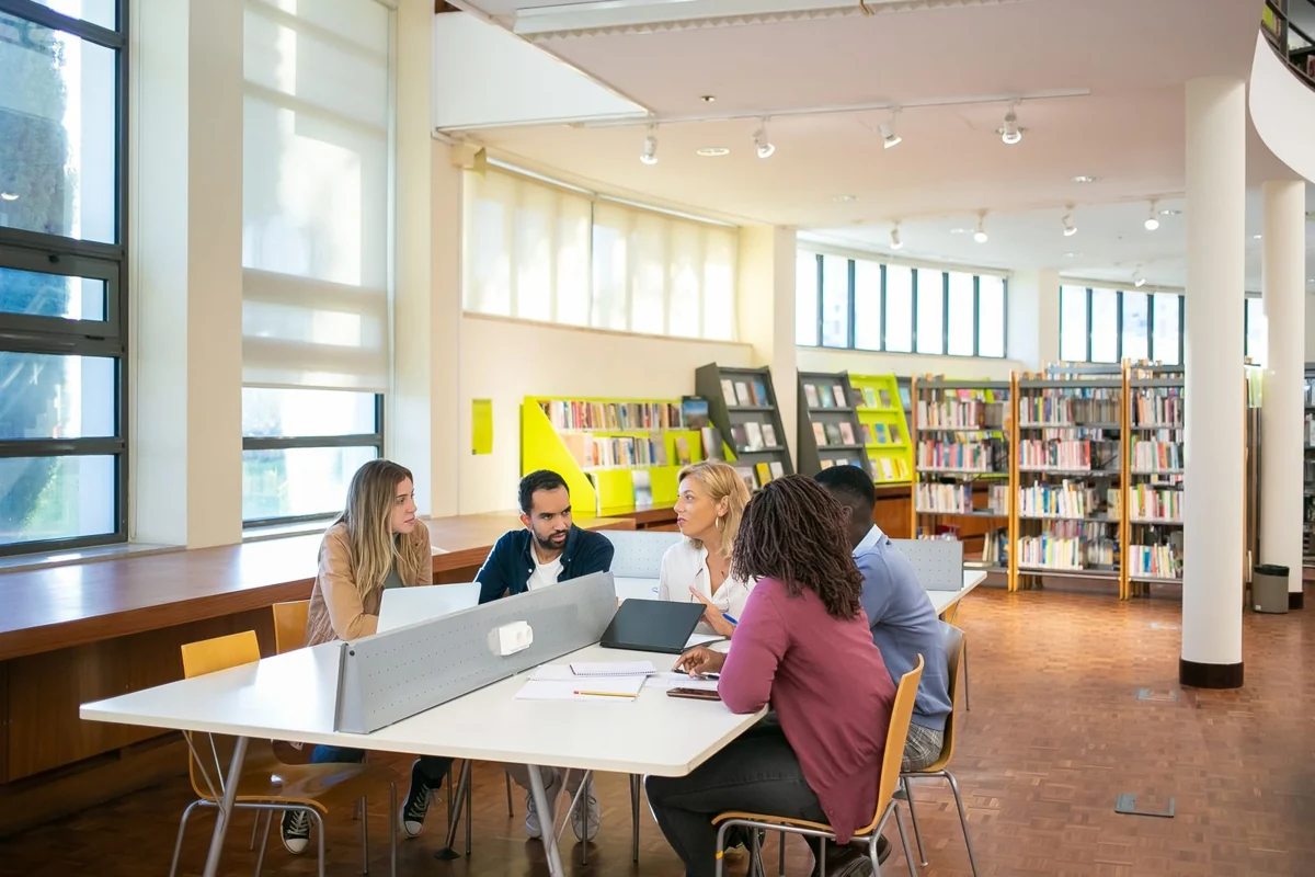Grupo de adultos estudando e colaborando em uma biblioteca