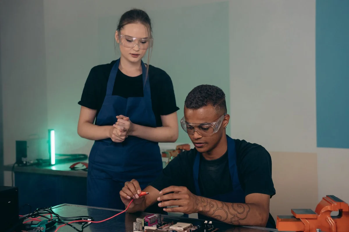Duas pessoas praticando atividades de eletrônica com óculos de proteção